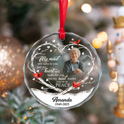 Memorial ornament with a photo of an elderly person and engraved text on a Christmas tree.