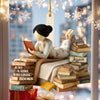 Decorative ornament of a girl reading books with 'Just a Girl Who Loves Books' text, against a blurred snowy window background.