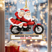 Decorative ornament of Santa and Mrs. Claus on a motorcycle with 'Growing Old Together Since 1998' text, against a festive background.